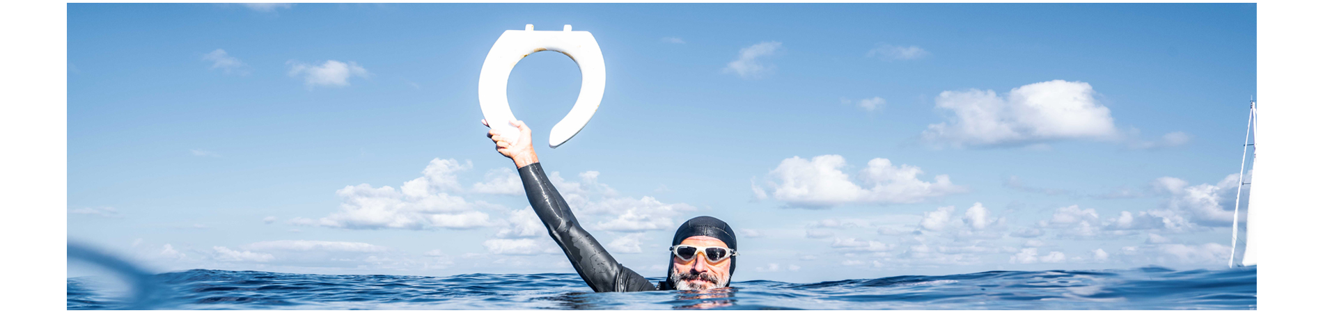 Man in ocean with googles holding a toilet seat