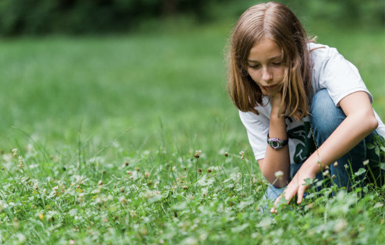 Girl in park looking for four-leaf clovers