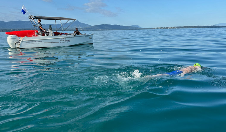 Neil Gilson swimming in Lake Geneva with support vessel close by